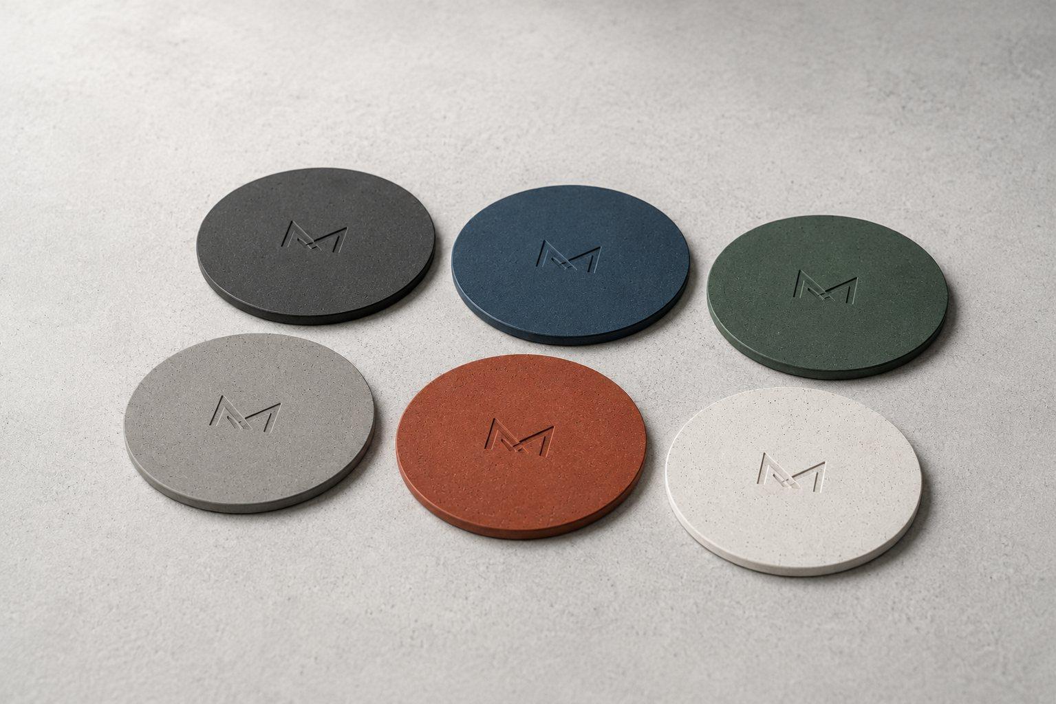 Set of round concrete coasters in six colors with a monogram recessed into each surface